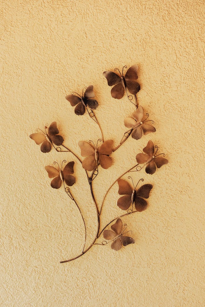 Artistic butterfly metal wall sculpture with detailed textures on a warm yellow background.